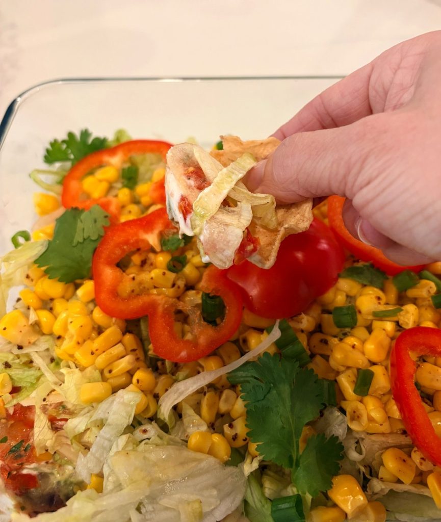 Tortilla chip scooping vegan 7-layer dip